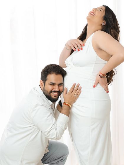 The pure joy of listening to the baby bump. This candid, happy moment is what makes a couple's maternity photoshoot so special.
