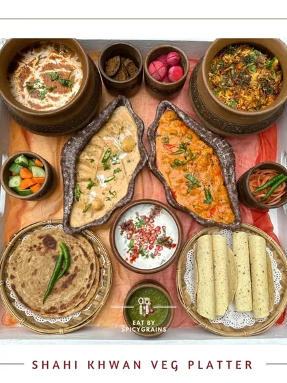 The Shahi Khwan Veg Platter, a complete meal that feels like a grand occasion. It includes rich curries, biryani, raita, and breads, all elegantly arranged on a single tray.