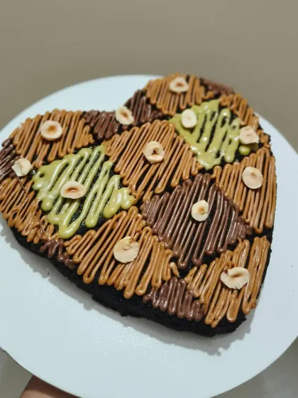This assorted heart-shaped brownie is for those who love variety. It's sectioned and decorated with different toppings, including Nutella, pistachio, and Lotus Biscoff spreads, and sprinkled with hazelnuts.