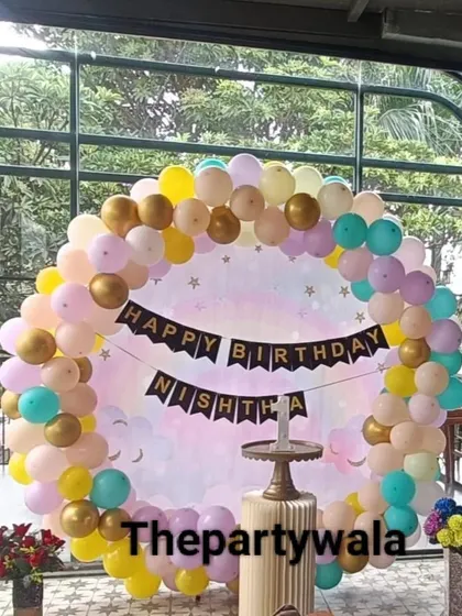 A pastel rainbow ring decoration against a large window. The natural light makes the colors of the balloons look even more beautiful.