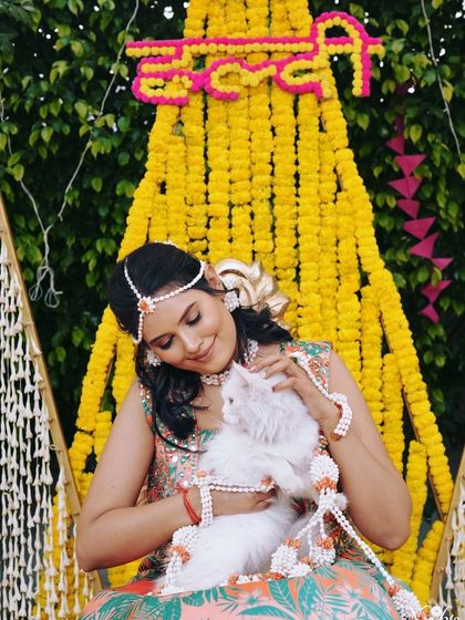 A playful moment with a furry friend during the Haldi celebrations. Her makeup is fresh and vibrant, perfect for the occasion.