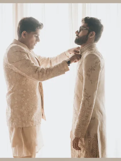 A quiet moment of brotherhood as the groom gets help with his outfit from his best man.