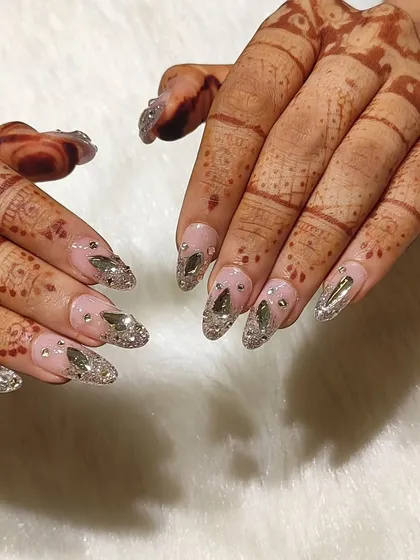 For the bride who wants to be the main character. This wedding nail set features a sheer pink base with a cascade of silver glitter and hand-placed, multi-faceted crystals for maximum sparkle that complements your mehendi.