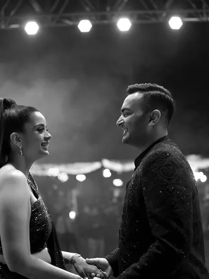 A candid black and white photo of the couple sharing a smile on the dance floor during their Sangeet.