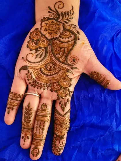 Another example of party henna, this one with a flowing paisley and floral design that moves diagonally across the palm.