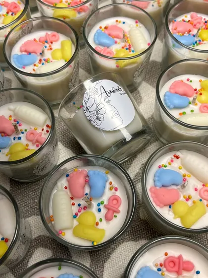 A closer look at the baby shower shot glass candles, showing the custom label and the cute, colorful wax decorations.