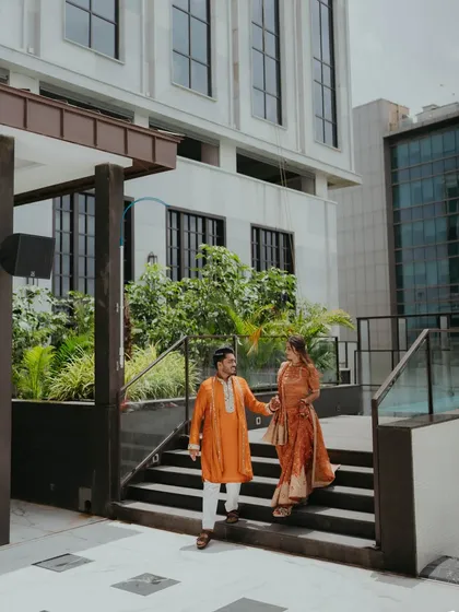 The couple, hand in hand, walking through the modern architectural spaces of the venue. We help find unique spots for your portraits.
