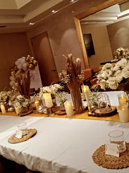 I also handle complete table arrangements for formal corporate dinners. This setup features a long table dressed with white floral bouquets, dried pampas grass, and numerous candles to create a warm and elegant dining experience.