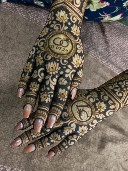A modern engagement design with the date and rings inside a lotus mandala. The other hand features the couple's initials.