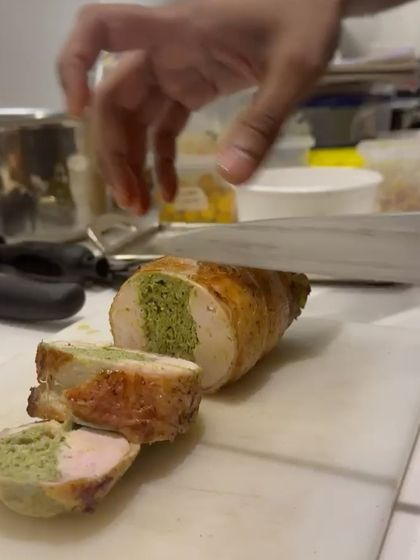 Another angle of the chicken ballotine being sliced, highlighting the juicy interior and the distinct layers of the roulade.