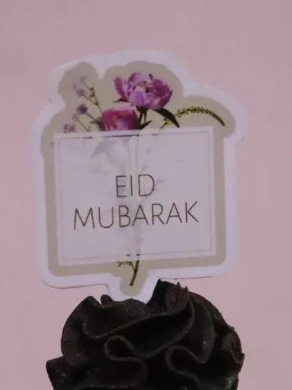A close-up of a single chocolate cupcake with a beautiful "Eid Mubarak" topper.