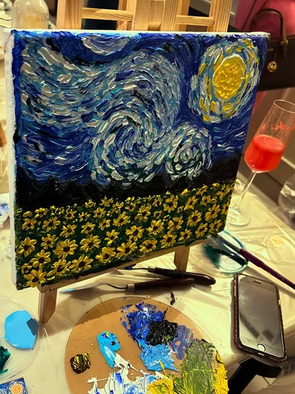 A 'Starry Night' inspired painting in progress, with a glass of wine nearby, perfectly capturing the sip and paint experience.