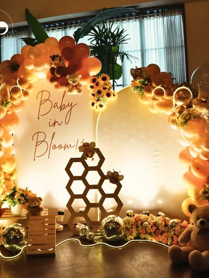 This "Baby in Bloom" celebration had a sweet honey bee theme. The warm, glowing setup features a custom backdrop with honeycomb details, surrounded by a cascade of orange and yellow balloons, sunflowers, and cuddly teddy bears for a buzz worthy event.