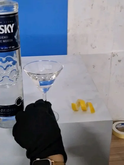 A behind-the-scenes look at styling a premium vodka shot, with a team member placing the lemon twist garnish.