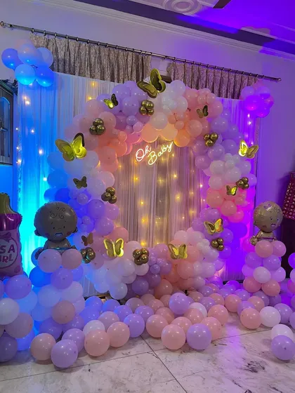 The complete baby shower setup with a pastel balloon arch, butterfly details, and character pillars.