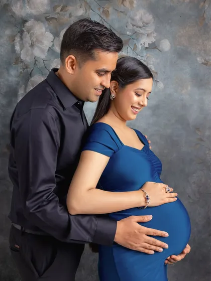 A close-up of the couple, focusing on their happy expressions and the gentle way they hold the baby bump.