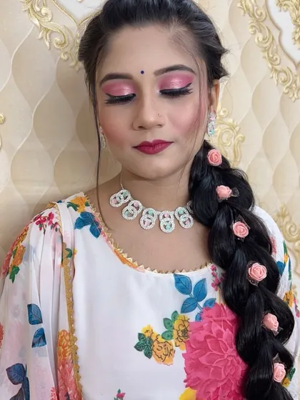 A close-up of the floral braid look, showing the soft pink eyeshadow and matching lip color. This is a perfect style for a mehndi or sangeet ceremony.