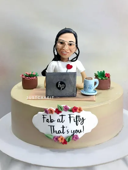 A "Fab at Fifty" cake with a custom half-figurine of a woman working on her laptop, surrounded by her pot plants. It's a great way to celebrate a modern working woman.