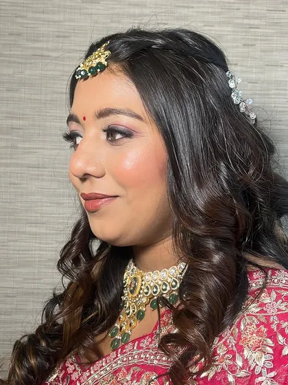 This side view showcases the soft curls and the beautiful way her makeup catches the light. The highlighter is placed strategically to give a radiant, not glittery, finish.