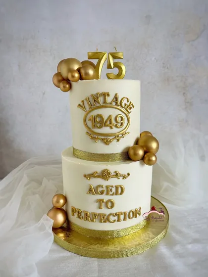 A classy and elegant cake for a 75th birthday. The white and gold color scheme is timeless, and the "Aged to Perfection" message adds a touch of vintage charm.