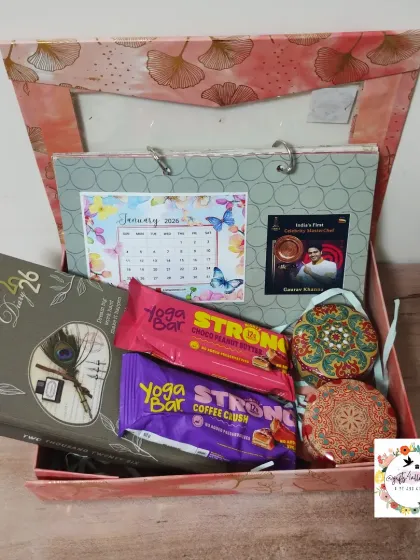 A New Year hamper featuring a personalized desk calendar, a 2026 diary, healthy energy bars, and scented candles, all packed in a beautiful custom box.