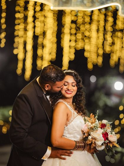 A romantic embrace against a backdrop of sparkling fairy lights. Nighttime portraits like this add a magical and dreamy quality to your wedding gallery.