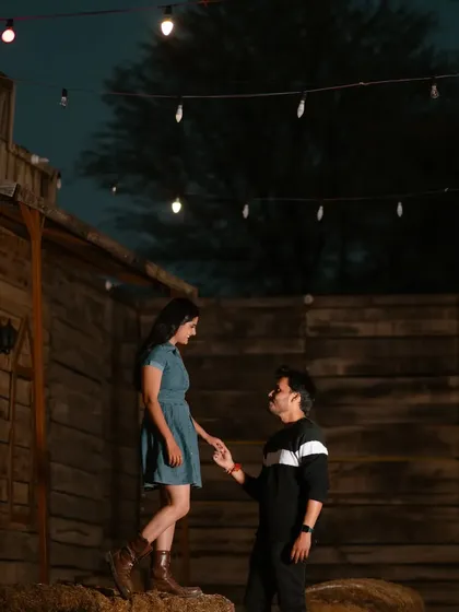 A rustic, western-themed night set. The string lights and wooden structures provide a unique and fun backdrop for a pre-wedding shoot with a different vibe.