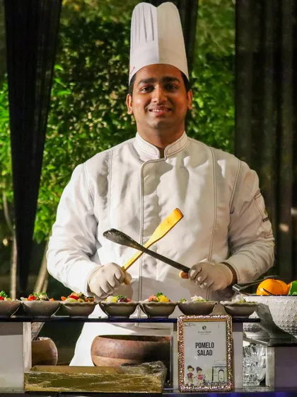 Our chef, ready with his tools, smiles proudly from behind his Pomelo Salad station. This is the face of our happy and dedicated team.