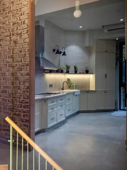 This open and airy kitchen uses white cabinetry and exposed brick to create a rustic yet modern feel. The layout is designed to be a living kitchen, integrated with the rest of the home.