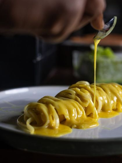 Taking the pasta game to a whole new level with the Linguine at Camillo's. A drizzle of yuzu butter sauce is being poured over the elegantly plated pasta.
