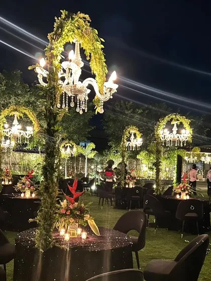 The full effect of the individual chandeliers over each round table, creating a sense of intimacy and grandeur in the open garden space.