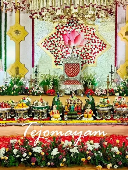 A symphony of colors, textures, and emotions. This Half-Saree ceremony setup features a grand floral backdrop and a detailed plate arrangement.