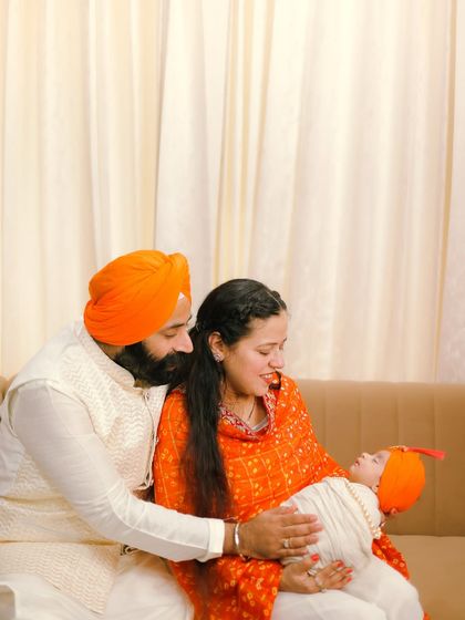 A quiet moment of adoration as a Sikh couple gazes at their newborn baby. The soft, warm lighting and their traditional attire add to the peaceful and loving feeling of this family portrait.