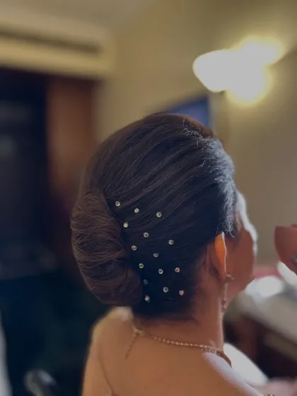 A classic French knot, elevated with delicate crystal pins scattered across the side. This is an understated yet very elegant updo, suitable for a sophisticated event or for the mother of the bride.