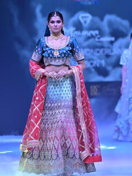 A full view of the stunning ombré lehenga on the runway. The contrasting red dupatta with a geometric pattern adds another layer of visual interest to this standout piece.
