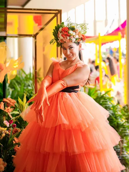 A performer in a vibrant, custom designed costume with a floral headpiece, posing within the event's lush decor. These details bring the theme to life in a tangible way.