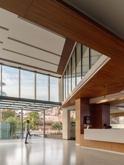The reception area of the Koramangala Club Annexe features a soaring, angled ceiling and a vast glass wall that floods the space with light. We designed this public building to feel open and welcoming, with clear sightlines and a sense of grandeur.