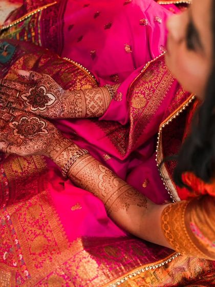 A top-down view of the henna stain, showing the rich color against a vibrant pink silk saree.