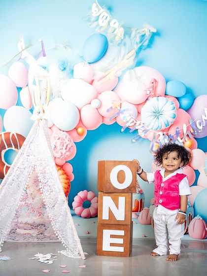 Standing tall next to the "ONE" blocks, this little boy is ready to celebrate. His bright pink vest adds a pop of color to the sweet pastel donut-themed backdrop.