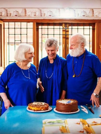 Nayaswami Jyotish and Devi share a laugh while cutting cakes. These candid moments show the divine friendship and lighthearted joy that are hallmarks of the spiritual life at Ananda.