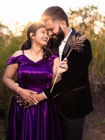 A golden hour pre-wedding shoot. The warm light beautifully illuminates this happy couple, highlighting the bride's rich purple off-shoulder gown.
