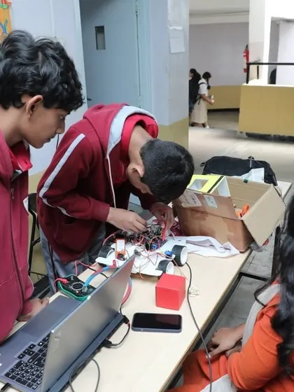 Teamwork in action. Students collaborate on a complex wiring task for their robot, learning to solve problems together and share ideas. This is a vital skill for any future engineer or innovator.