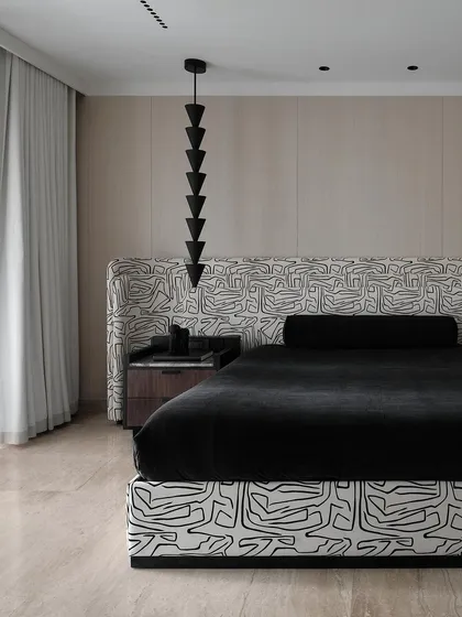 A side view of the master bed, highlighting the contrast between the bold patterned fabric and the simple, clean lines of the wall paneling and bedside table.