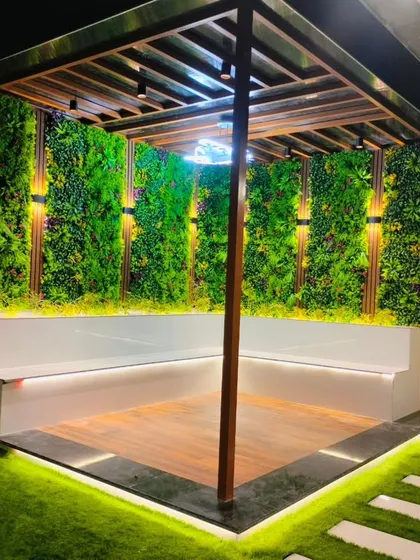 A completed pergola in Sonipat, designed for relaxation and social gatherings. The structure features built-in L-shaped seating, vertical garden walls for privacy and greenery, and integrated lighting to create a warm and inviting atmosphere at night.
