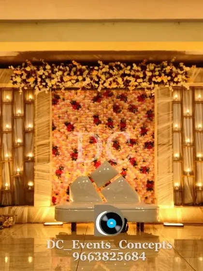 A sophisticated Sangeet stage with a floral wall and candle-lit panels. The modern sofa and warm lighting create an intimate and stylish ambiance for an evening of music and dance.