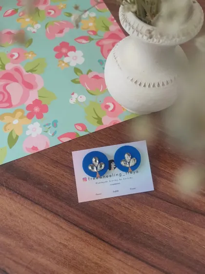 A collection of my simple and elegant fabric studs. Each pair is hand-painted with a small leaf motif and comes in a variety of colors like green, white, yellow, blue, and pink.