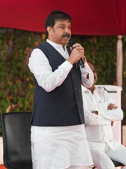 Politician Prasad Lad addressing a gathering in a classic white kurta and black Nehru jacket. An outfit that commands respect and exudes confidence.