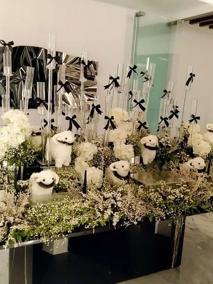 A modern and whimsical tablescape with white floral arrangements and smiley-faced props, all tied together with black bows.