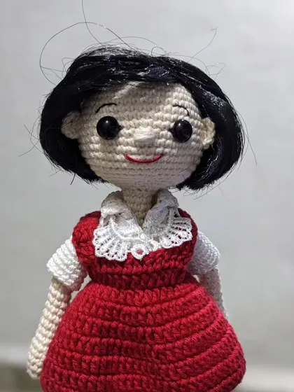 A close-up of a custom doll made as a gift for a 'jija' (sister-in-law), featuring a lovely red dress with a delicate lace collar.