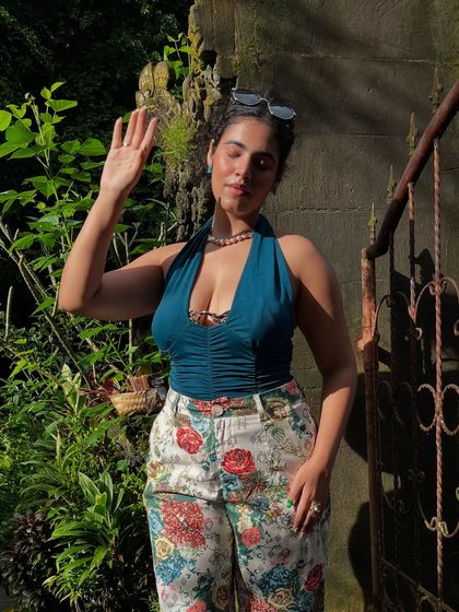 This Barbie is not made for laptops and 9-5s. A sunny shot of me in the lush greenery of Ubud, wearing floral pants and a teal top.